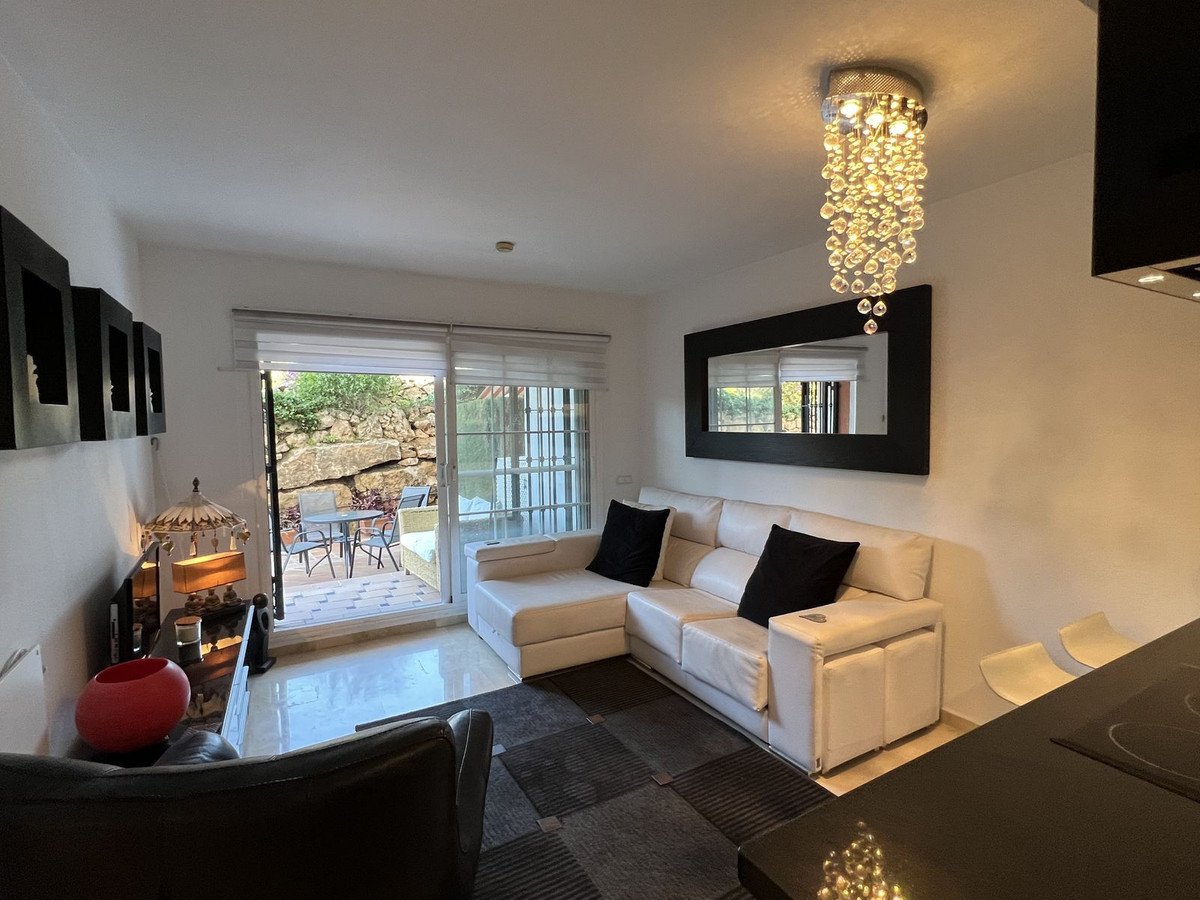 Modern living room with white sofa, black pillows, and a view of the beach through large windows
