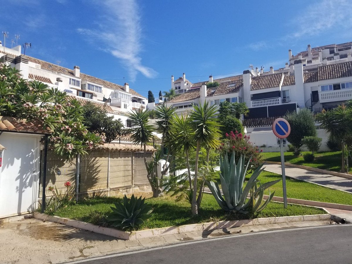Residential street with palm trees, agave plants, and white buildings under blue sky
