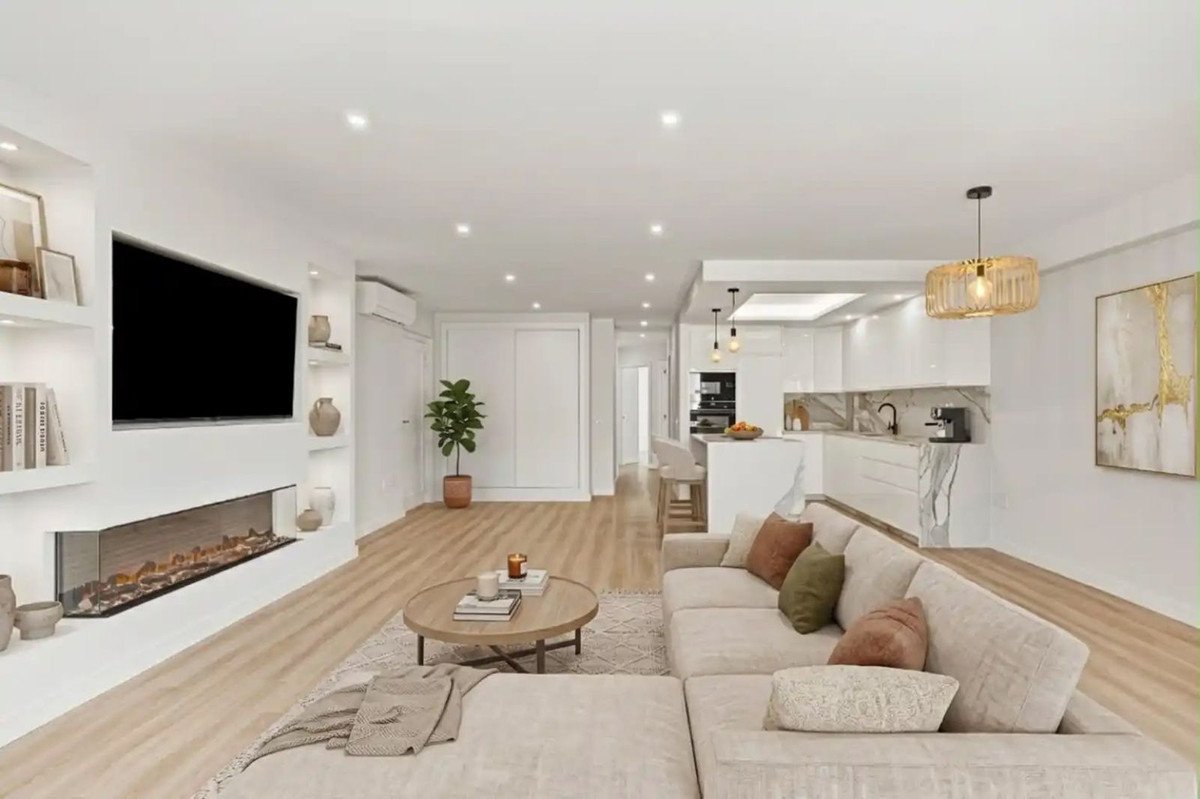 Spacious living room with modern fireplace, large sectional sofa, and open-plan kitchen with island and bar stools.
