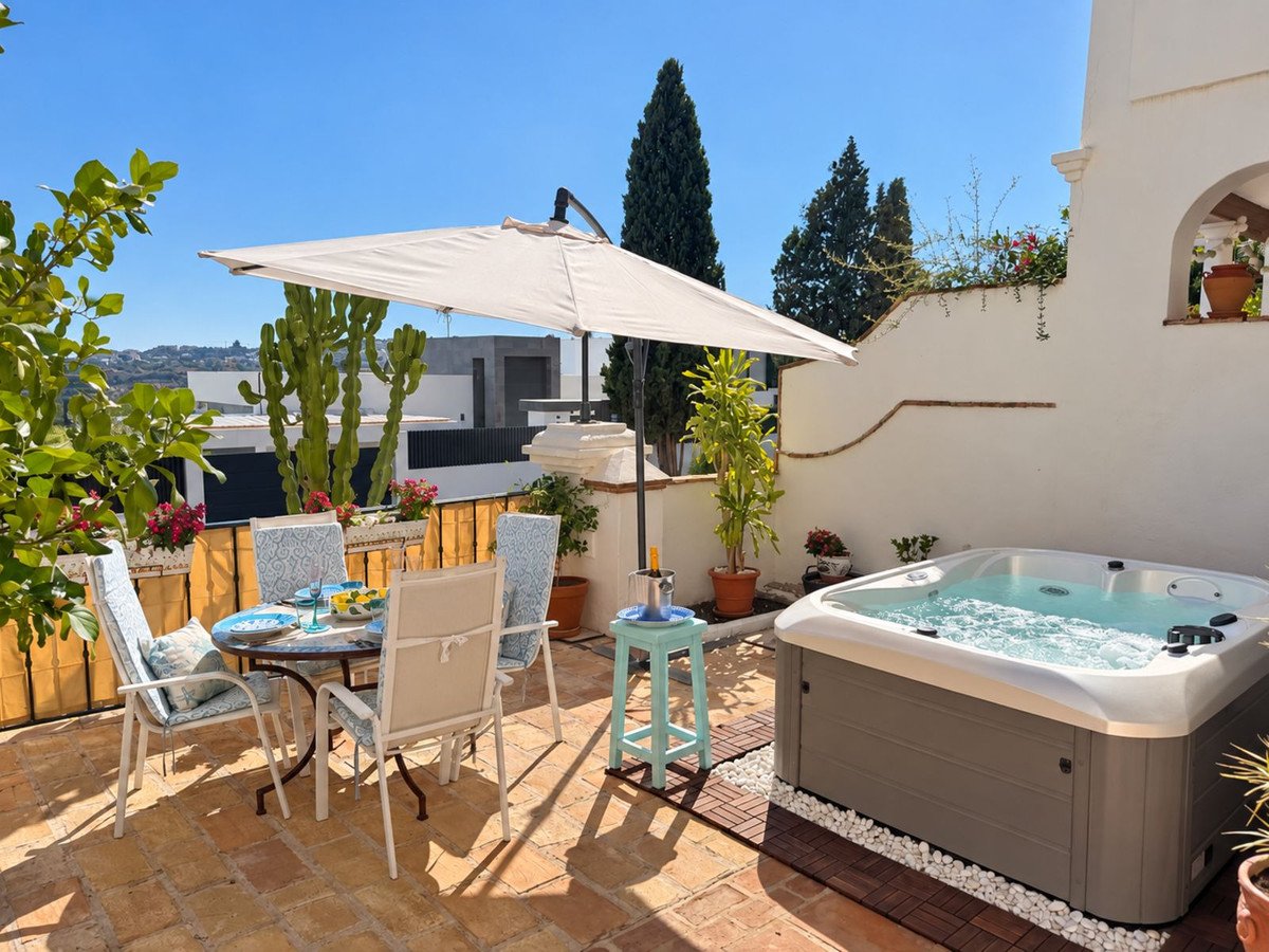 Rooftop terrace with hot tub, outdoor dining, and potted plants under sunny sky