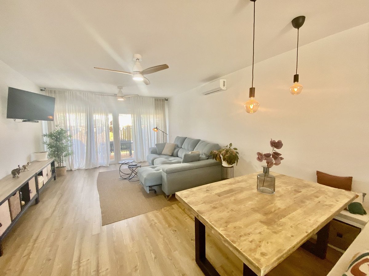 Modern living and dining room with natural light, a sectional sofa, dining table, TV, and ceiling fans. Access to an outdoor space through patio doors.
