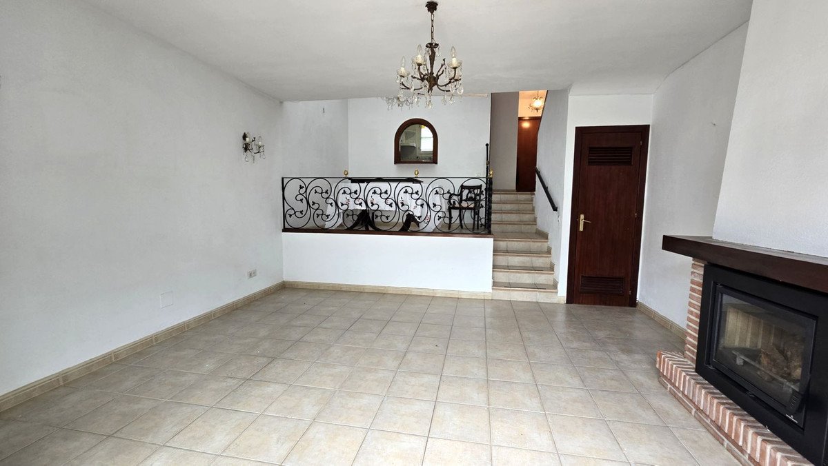 Empty living room with tiled floor, fireplace, and staircase leading upstairs