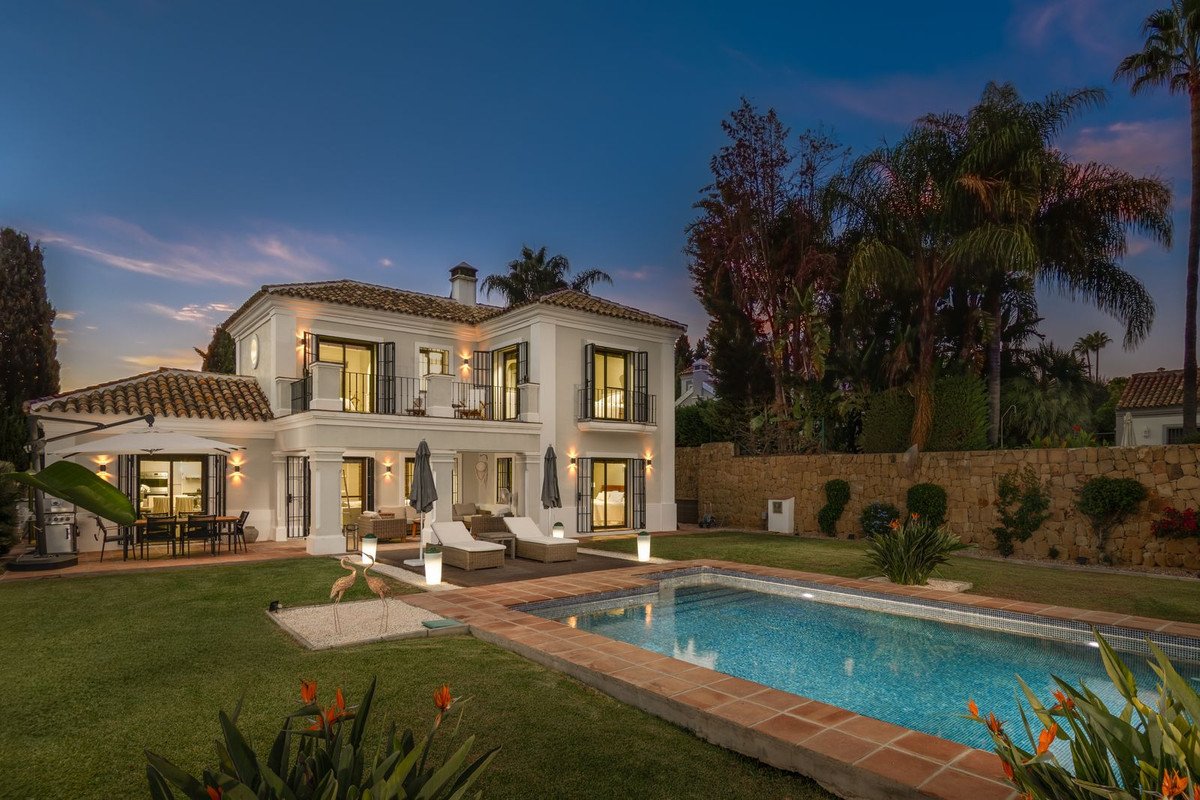 Luxury villa with swimming pool, terrace, and outdoor dining area at dusk.