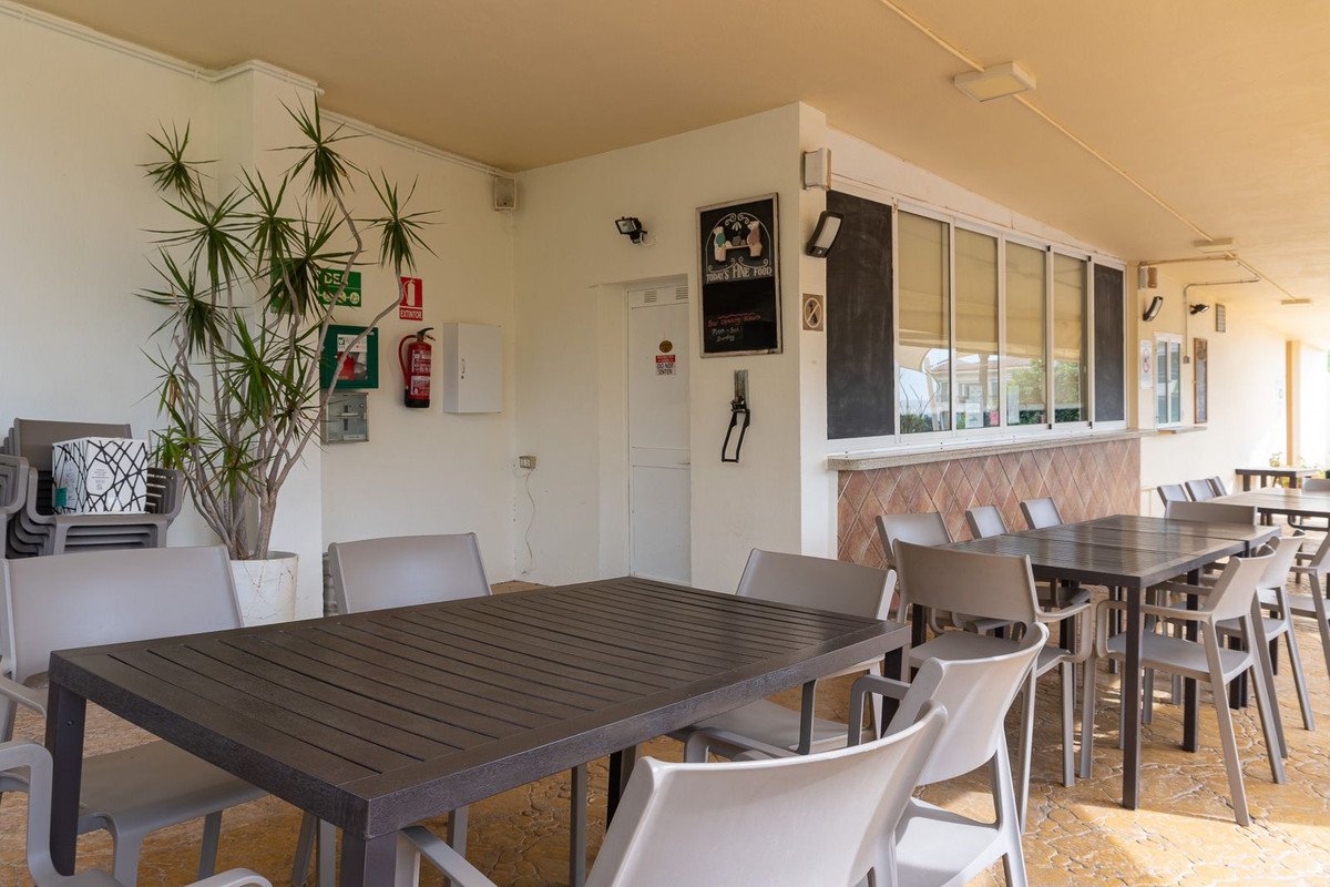 Covered outdoor dining area with tables, chairs, and a potted plant.