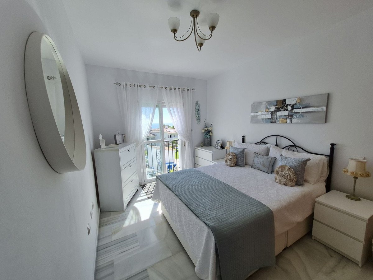 Modern bedroom with a king-size bed, abstract art, a large mirror, and a balcony with a sea view.