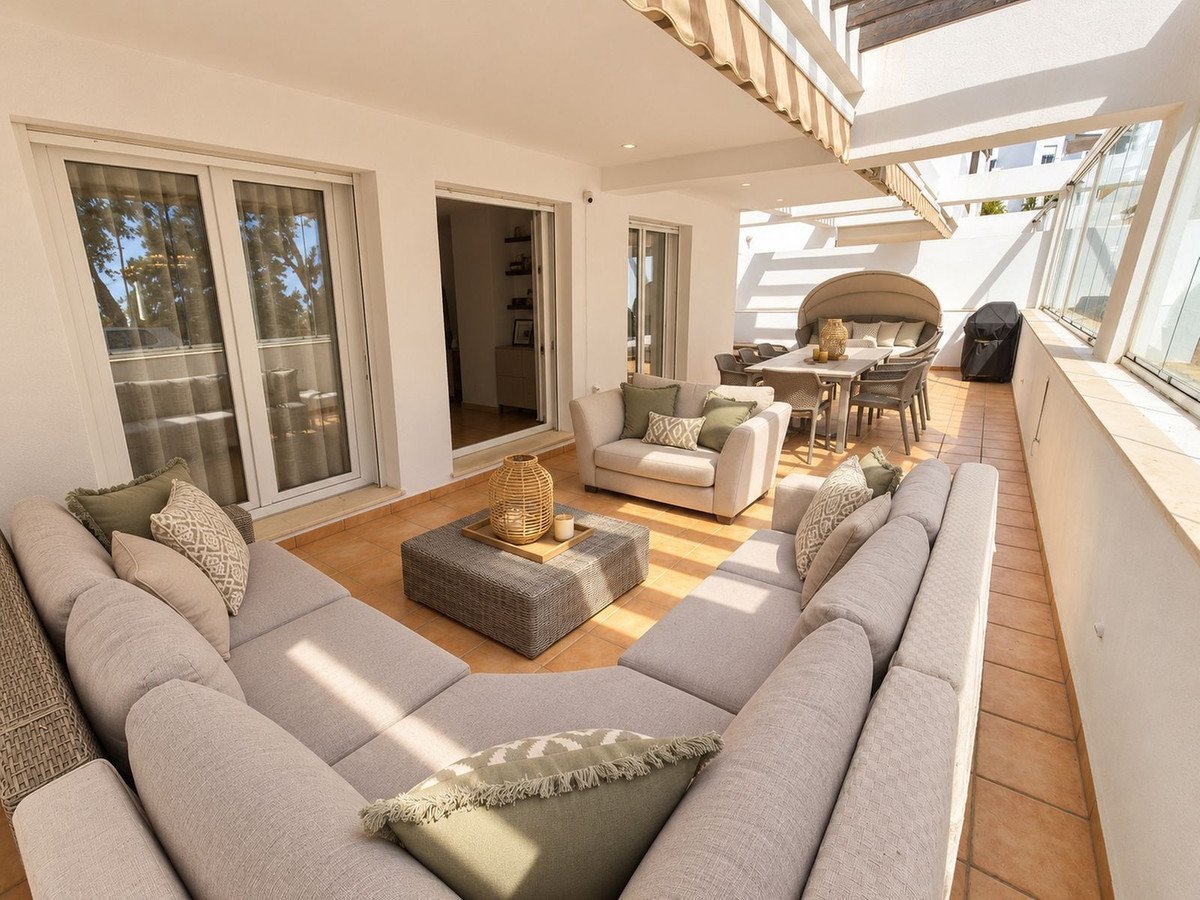 Spacious terrace with a large modular sofa, dining table with chairs, and a grill. Ideal for outdoor living and entertaining.
