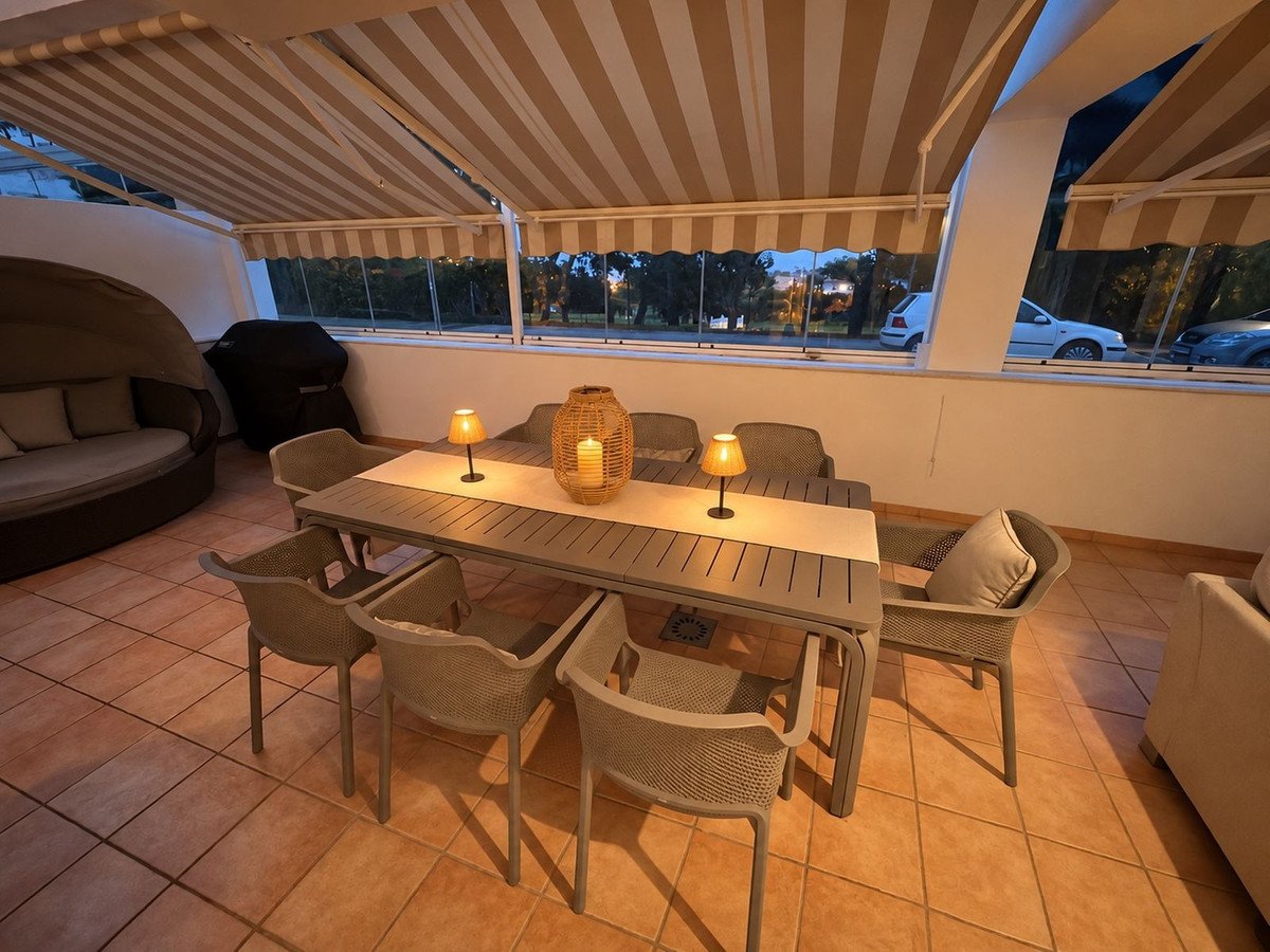 Terrace with a dining table, chairs, and a daybed, featuring a grill and ambient lighting.
