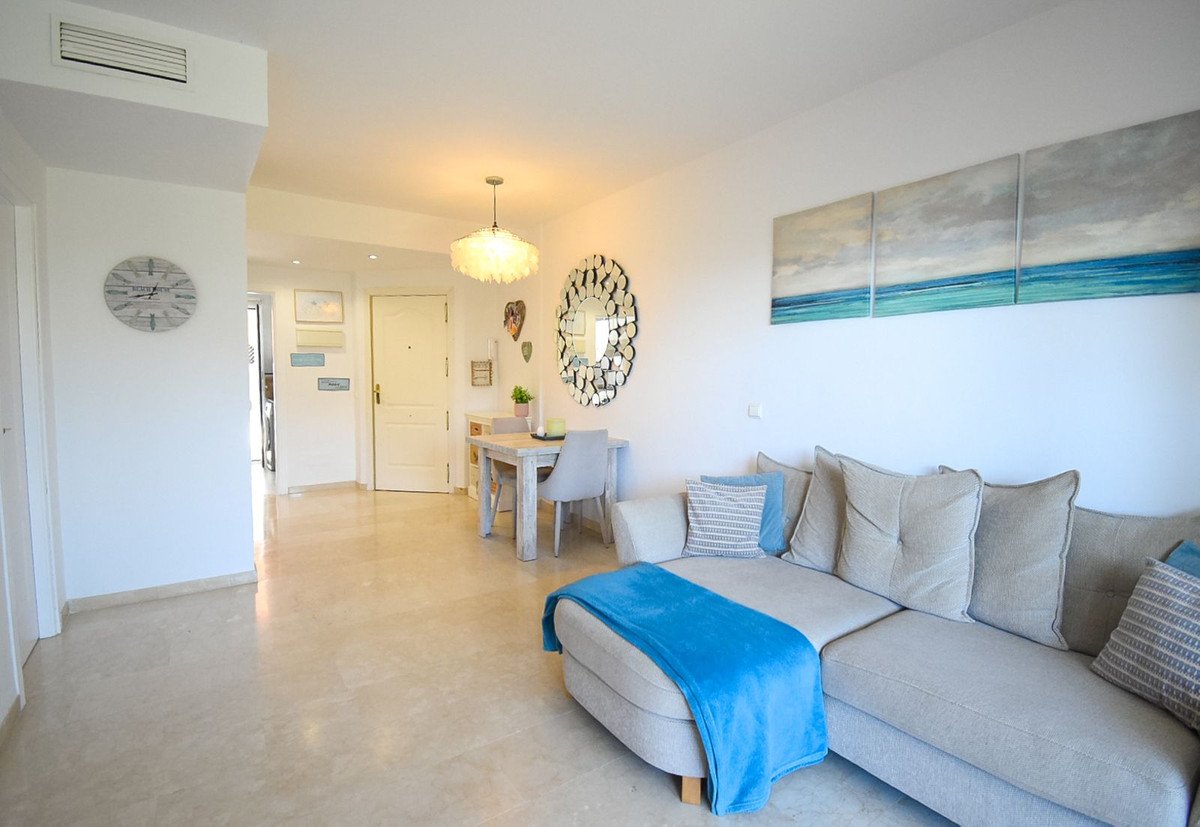 Spacious living and dining area with comfortable sofa, coastal artwork, and bright natural light.