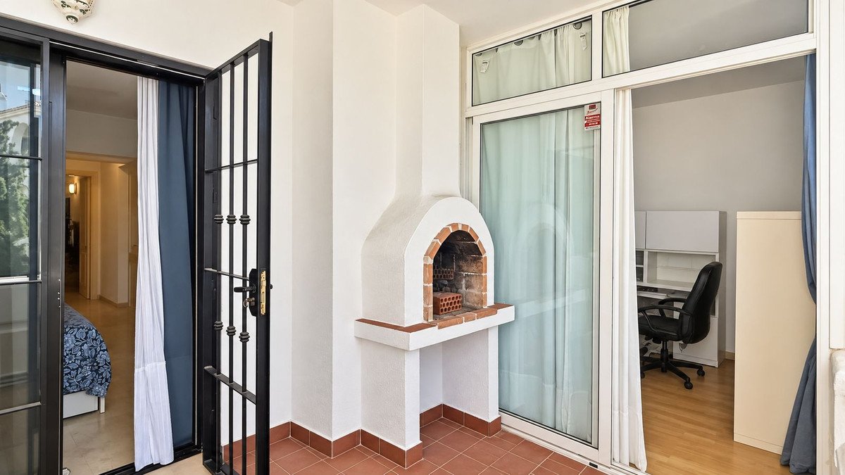 Terrace with a built-in BBQ, overlooking a bedroom and a home office area with large sliding glass doors.