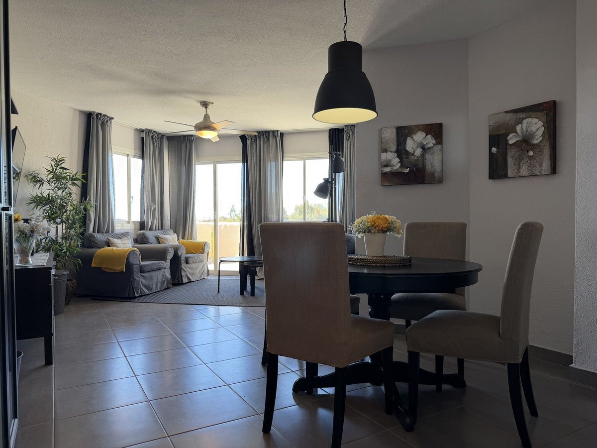 A spacious living and dining room area with comfortable seating, a dining table, and large windows offering natural light and a view.