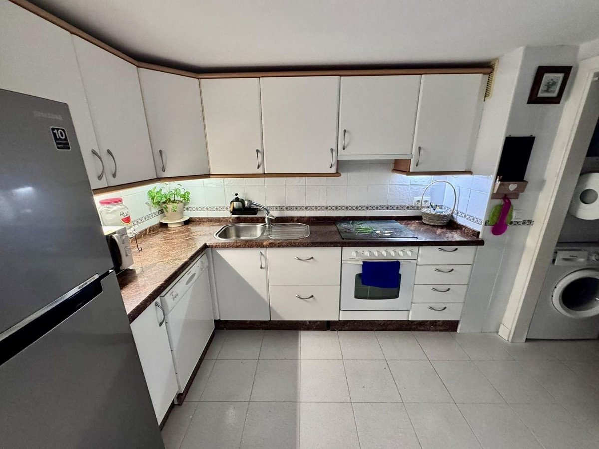 A compact kitchen with white cabinets, stainless steel refrigerator, stove, sink, and granite countertops.