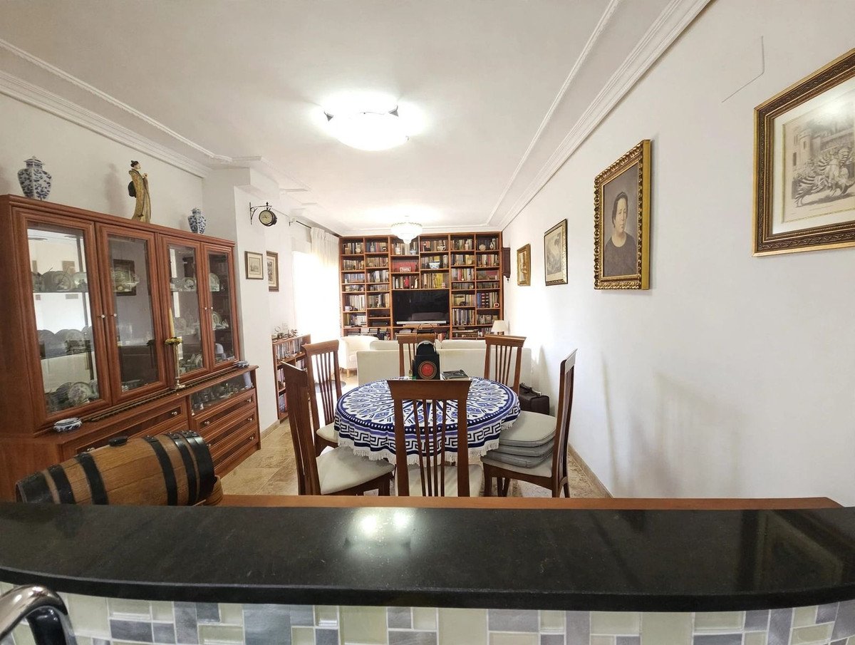 Living and dining area with large bookshelf, dining table, and display cabinet filled china cabinet.
