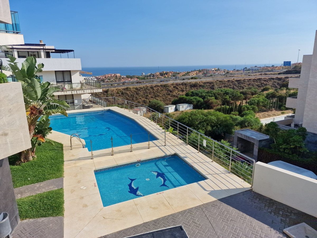 Two swimming pools with dolphin mosaics and a view of the sea from a balcony.