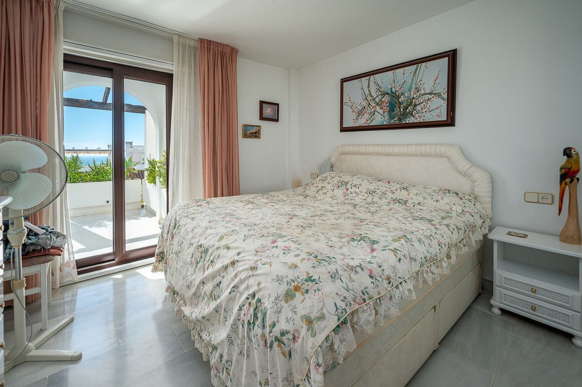 Bedroom with floral bedspread, sliding doors to balcony with sea view