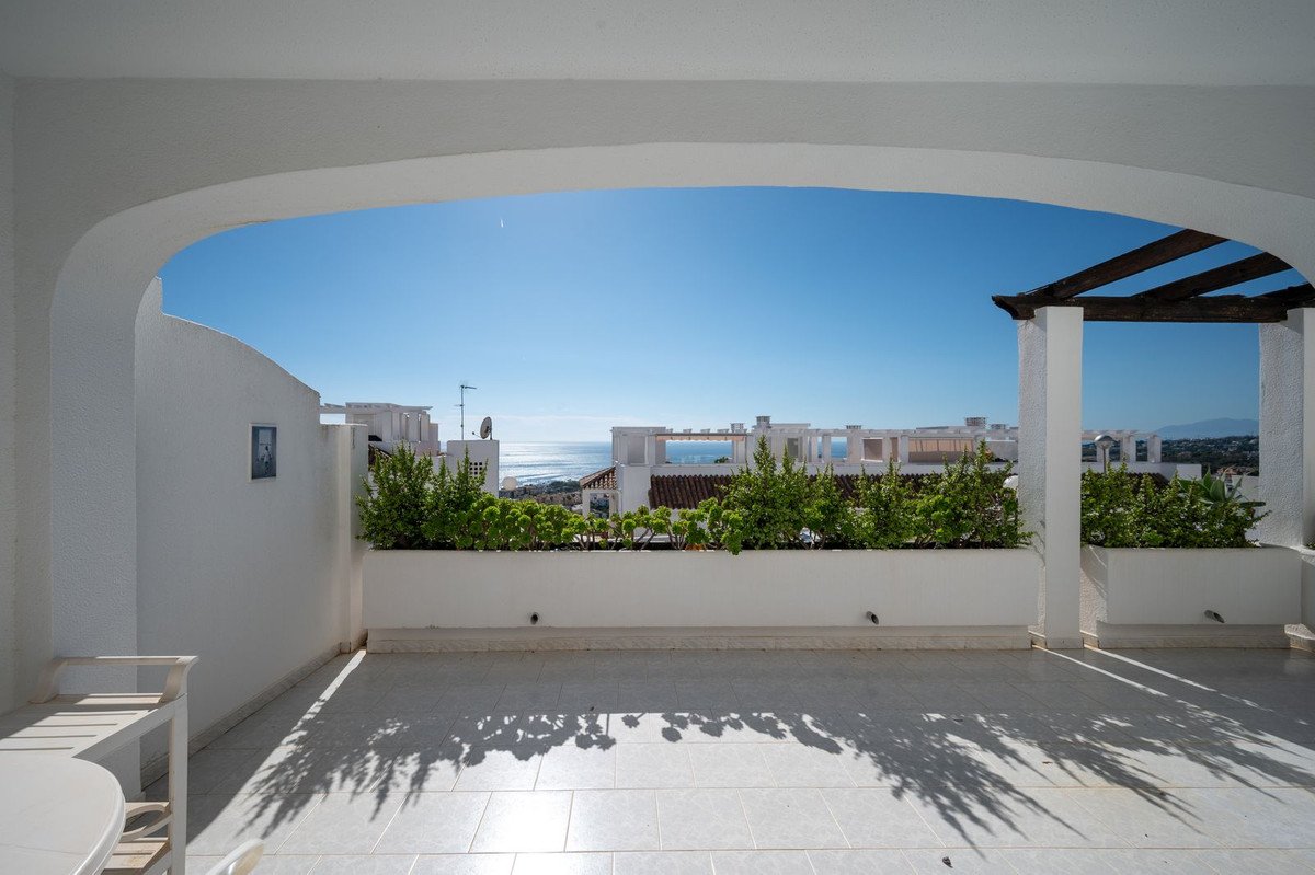 Bright terrace with white walls, sea view, and outdoor seating