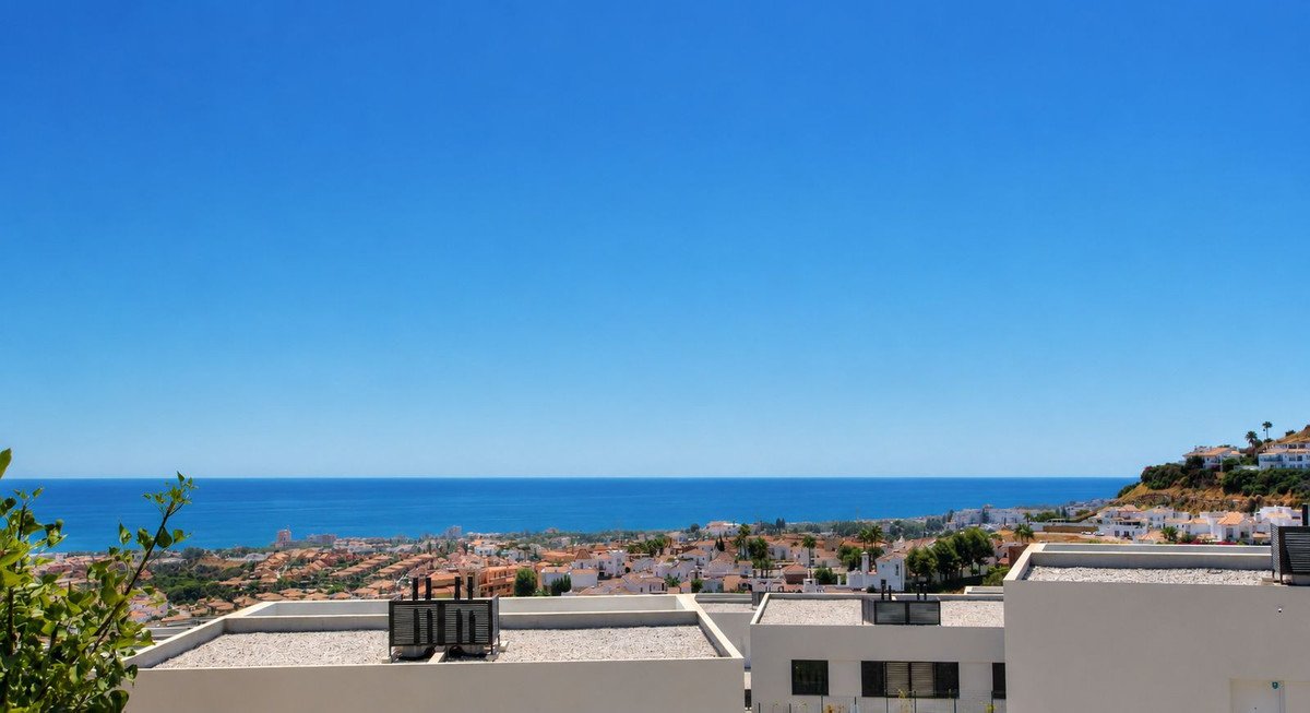 Spacious terrace with a stunning sea view overlooking a coastal town and blue ocean under a clear sky.