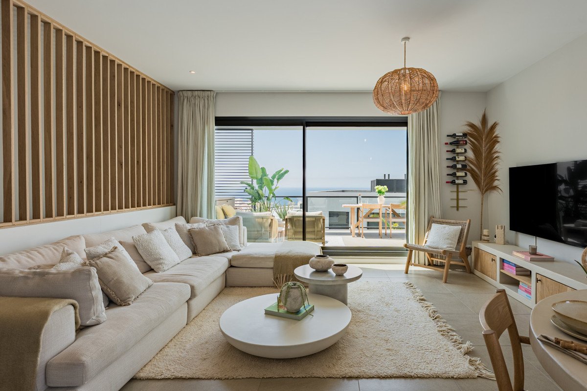 Modern living room with a large sectional sofa, coffee tables, and a balcony with a sea view.