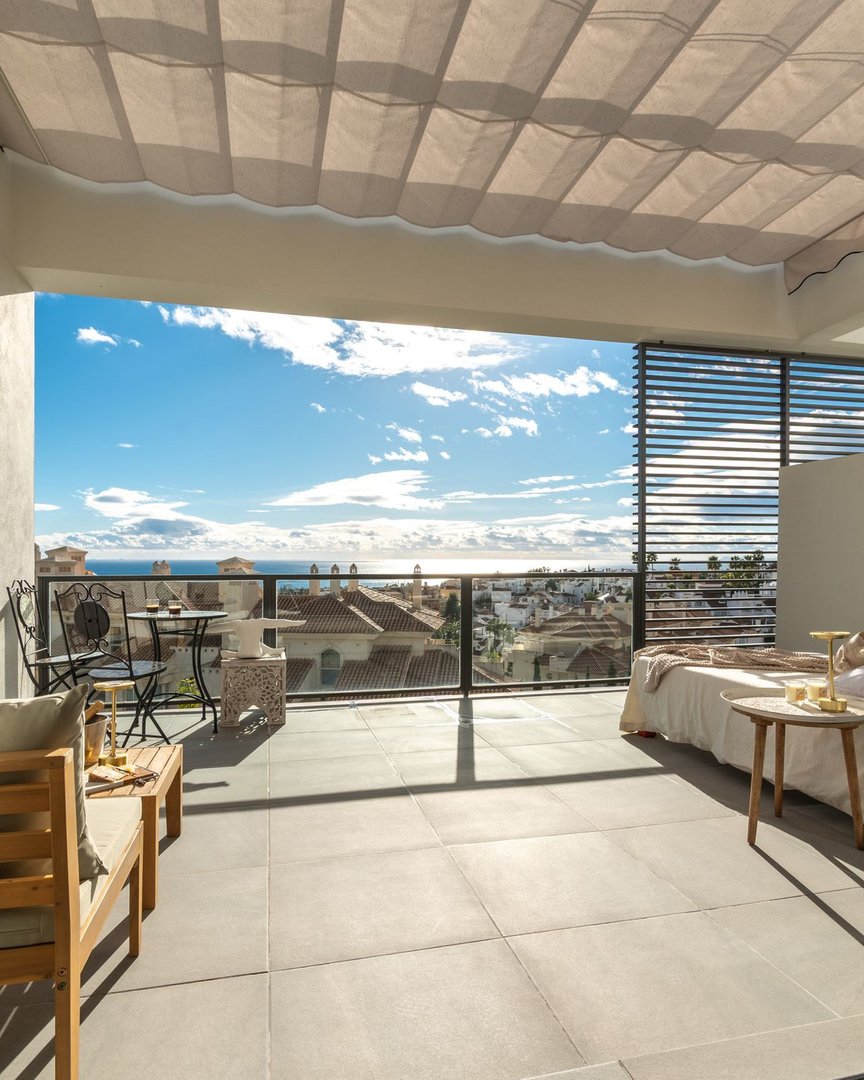 Balcony with sea and city views, featuring outdoor seating and a bed with a view.