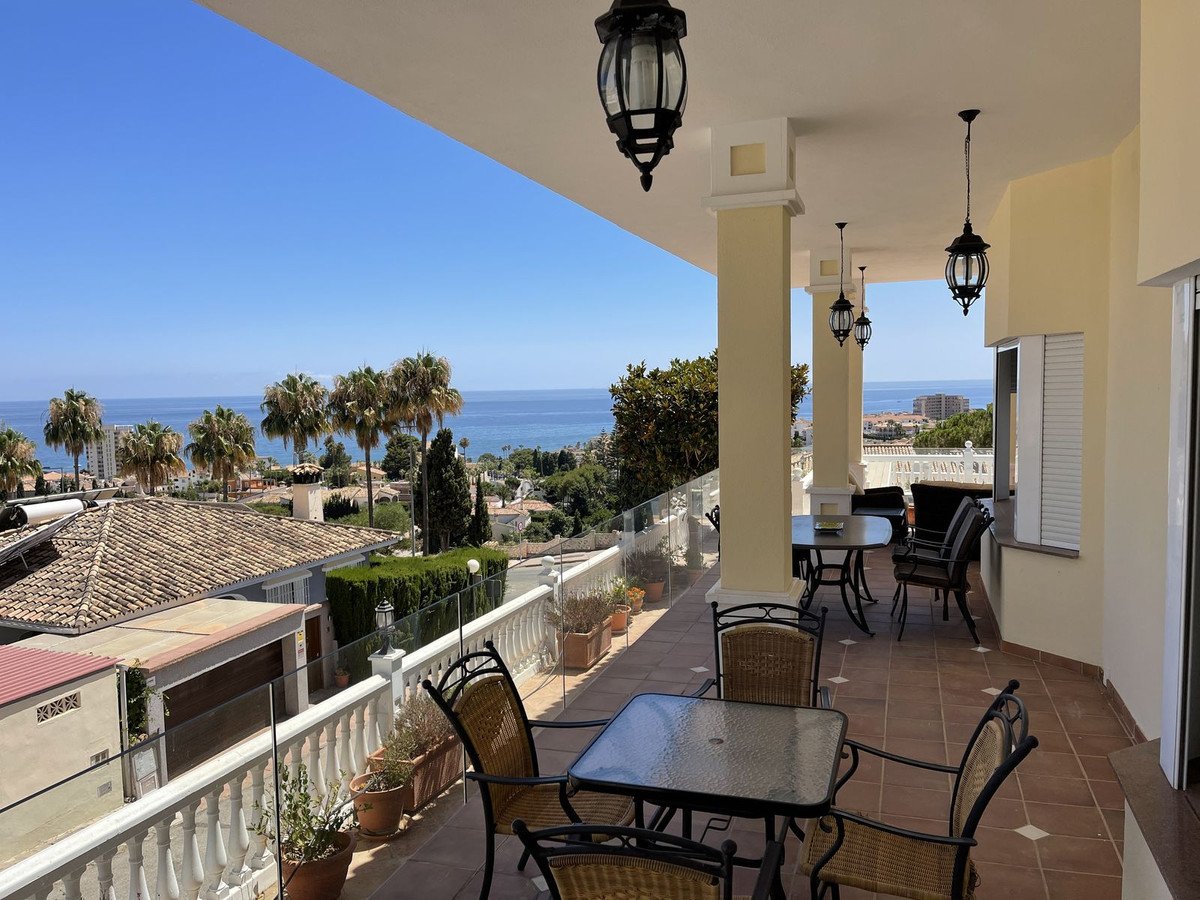 Spacious terrace with dining furniture and panoramic sea views, palm trees, and residential buildings.