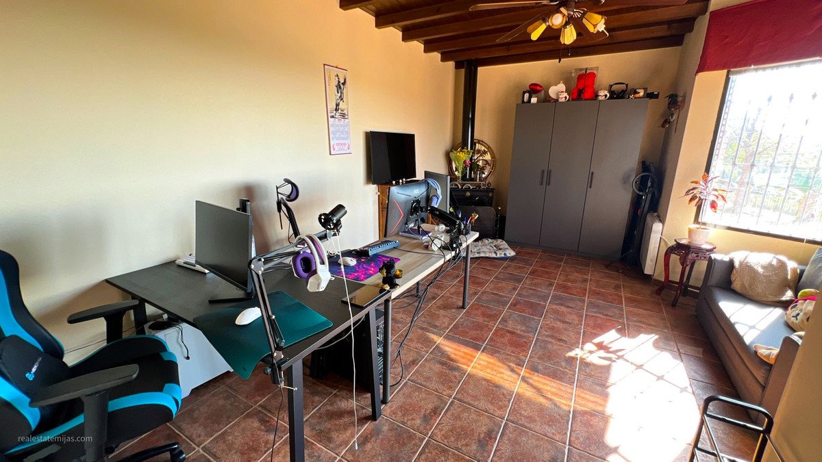 Sunlit room with tiled floor, computer setup, couch, and large window.