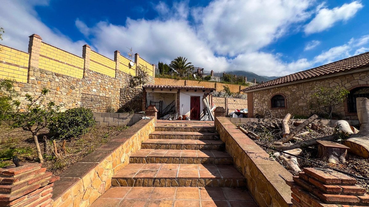 Traditional stone house with red-tiled roof, courtyard, and mountain view.