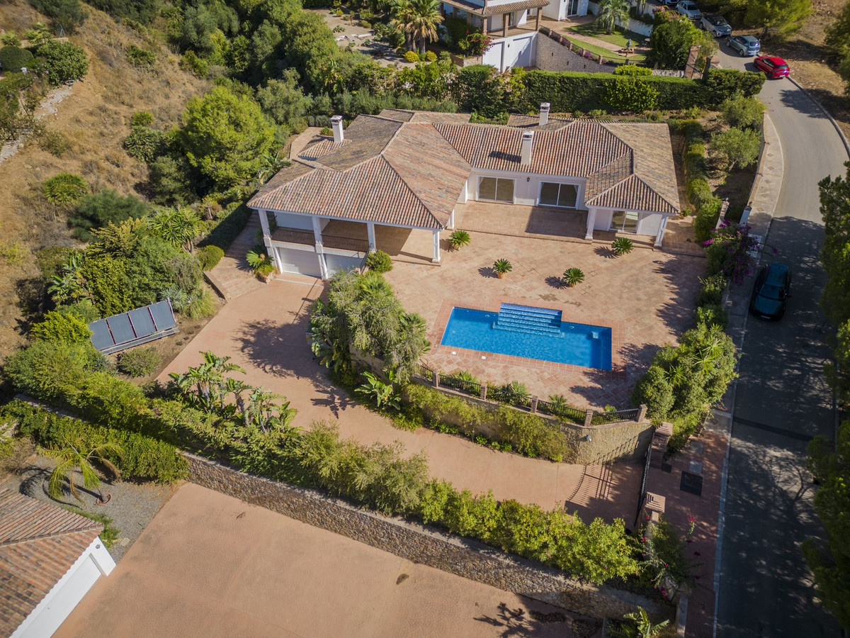 Aerial view of a two-story house with a swimming pool, surrounded by greenery.