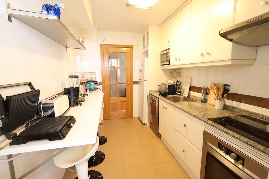 Moderne keuken met witte kasten en apparatuur.