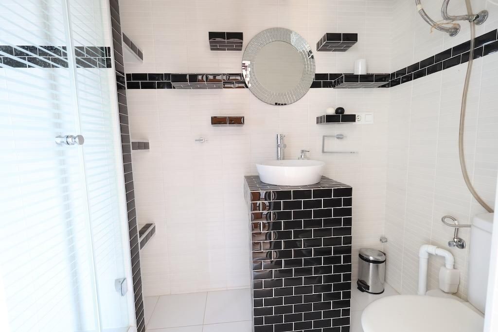 Moderne badkamer in zwart-wit met wastafel en douchecabine.