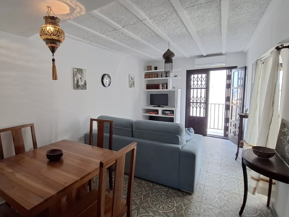 Cozy living and dining area with a blue sofa, wooden furniture, decorative lamps, and access to a balcony.
