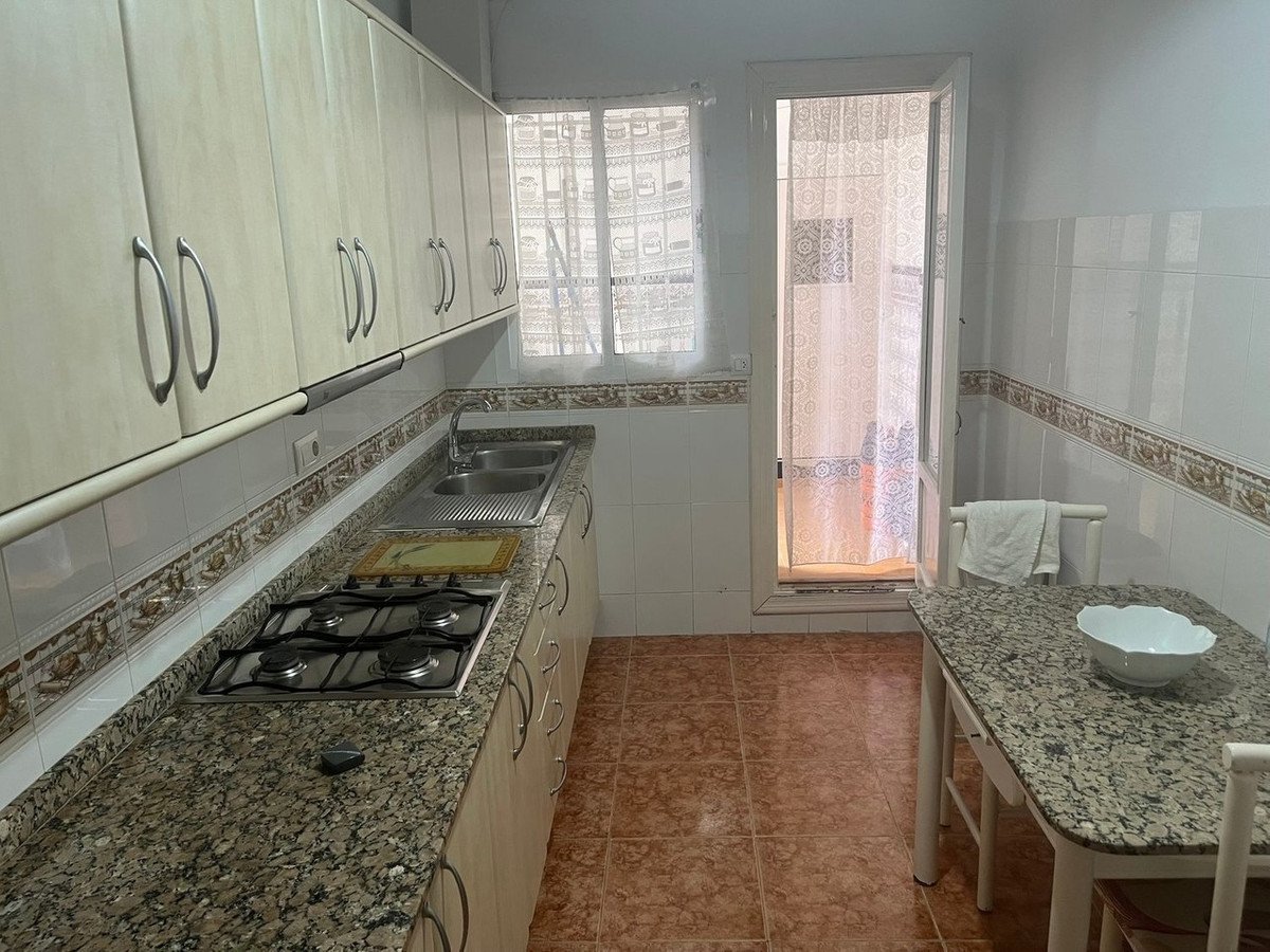 A kitchen with granite countertops, cabinets, gas stove, and a small dining table.