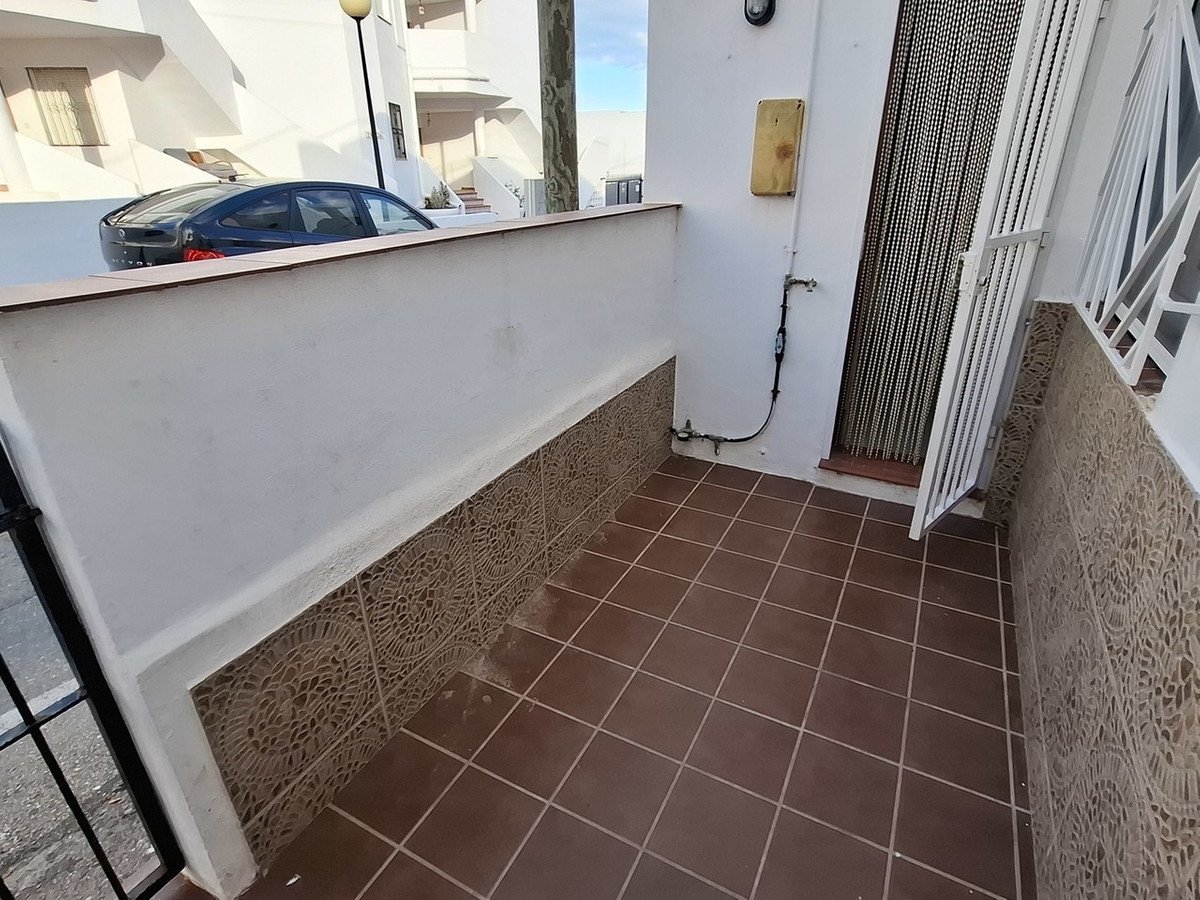 Tiled terrace with decorative walls and view of a car and buildings