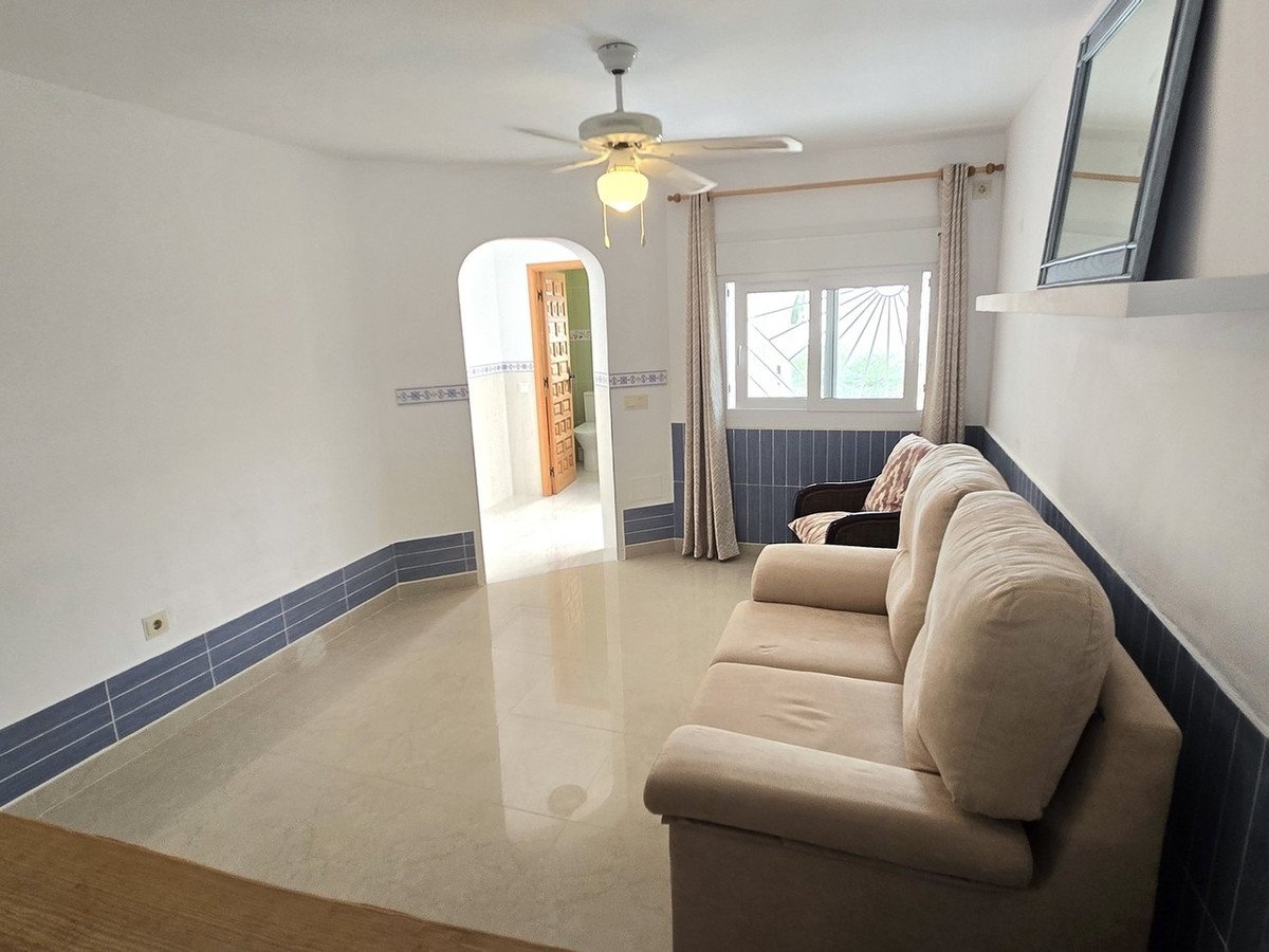 Living room with beige sofa, ceiling fan, and tiled walls