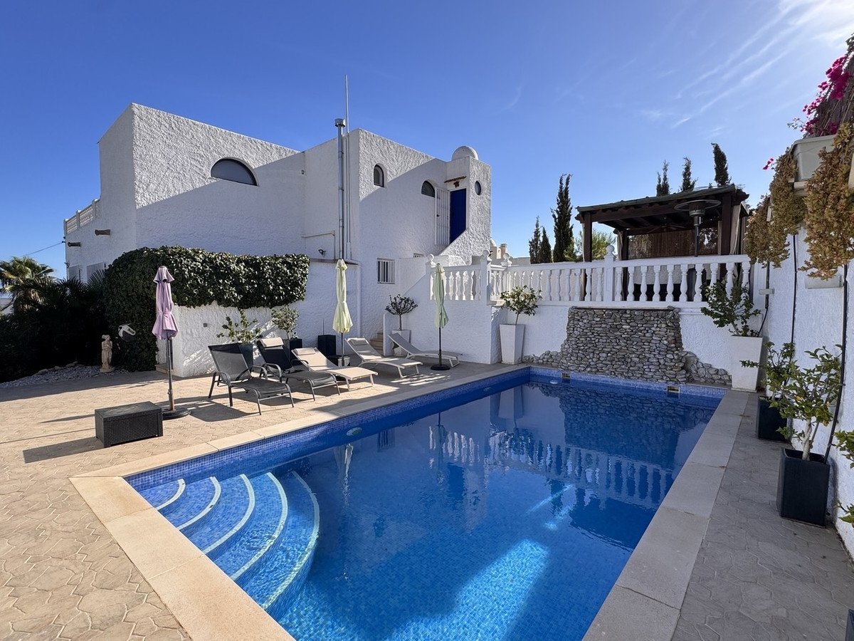White villa with swimming pool and sun loungers on a sunny patio