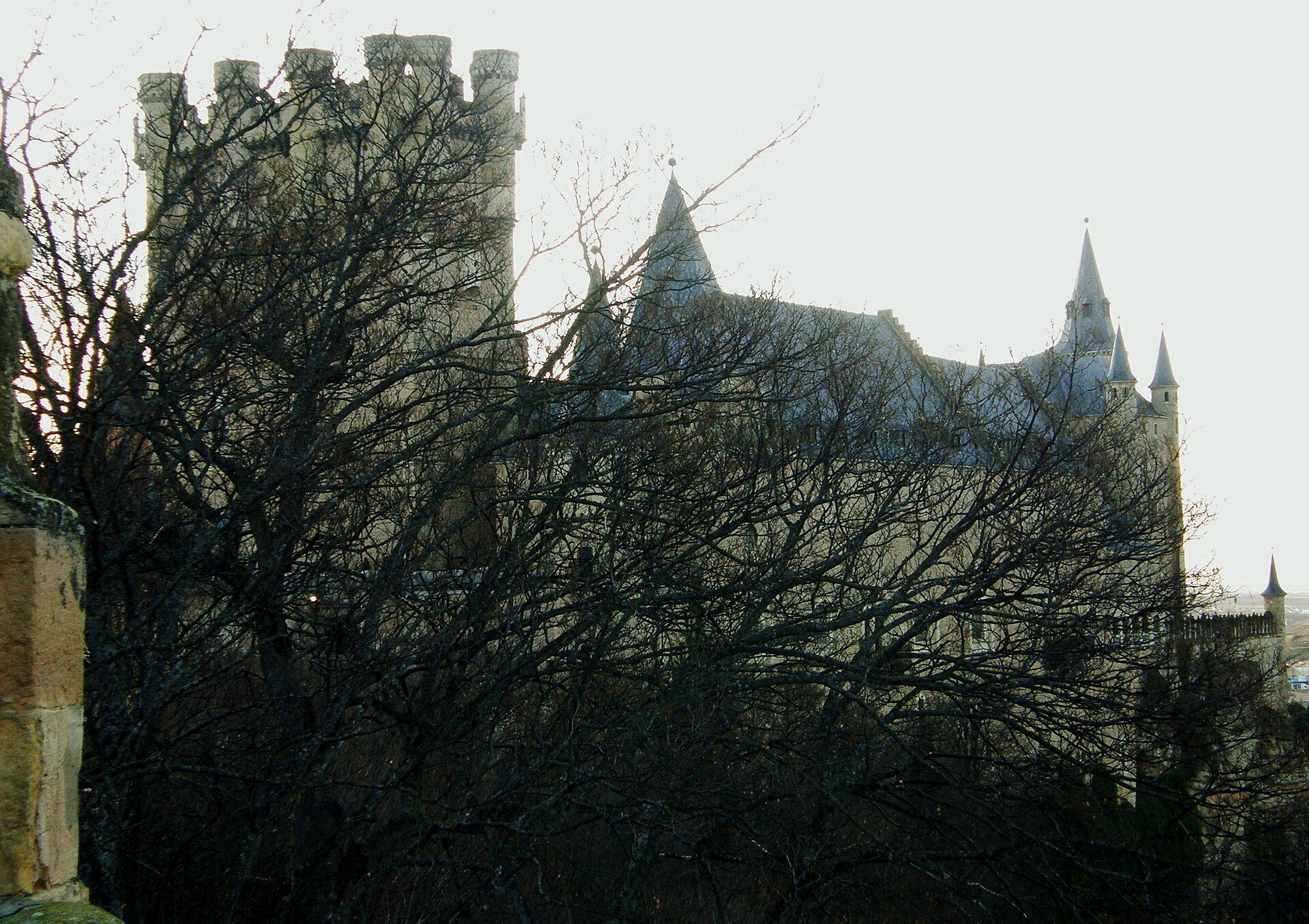 A medieval castle with a view of the surrounding landscape, featuring stone walls and towers.