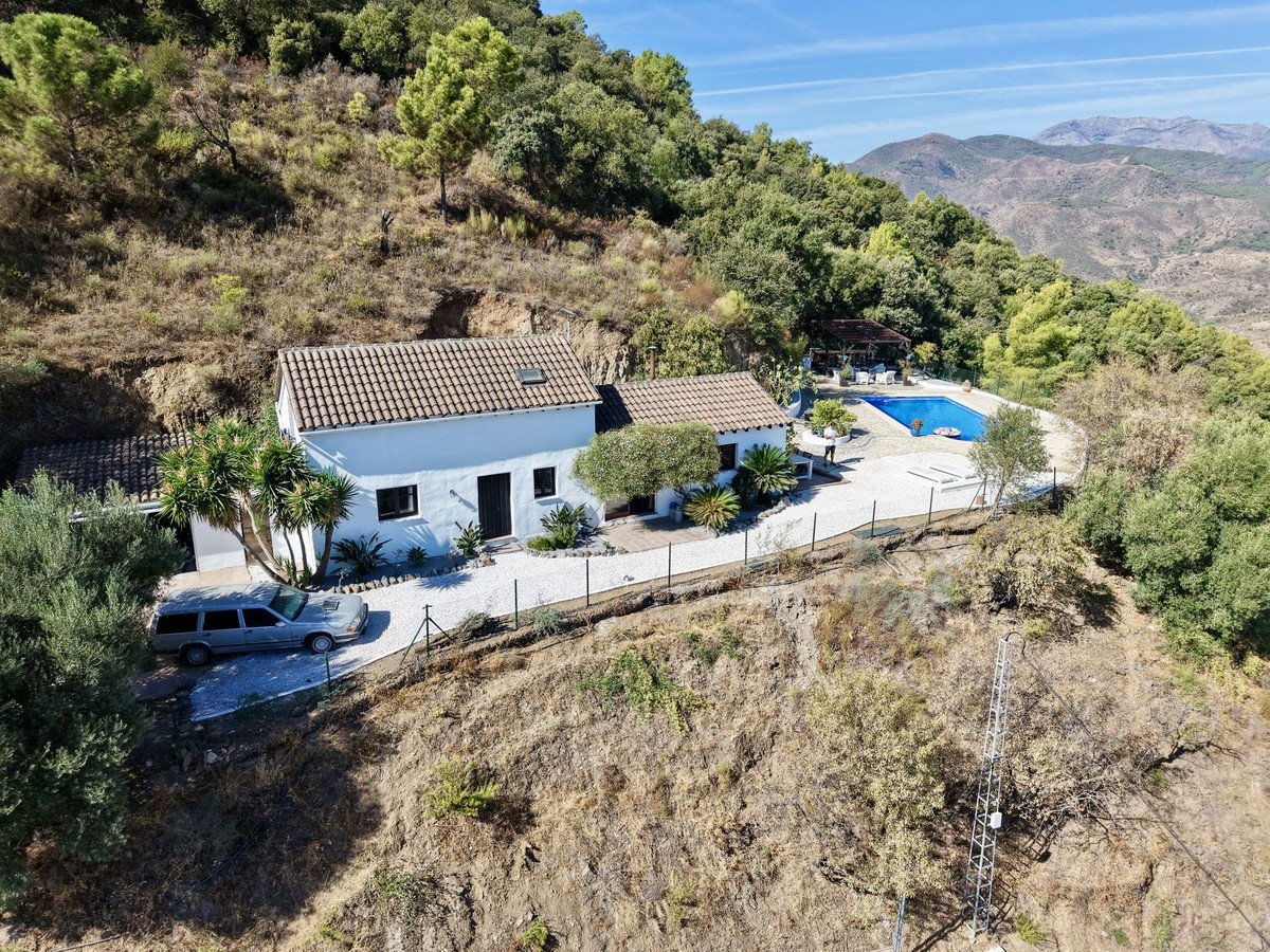 White villa with a swimming pool, covered seating area, and expansive mountain views on a sunny day.
