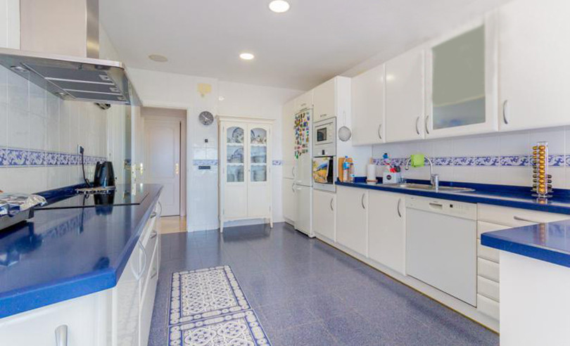 Lichte witte keuken met blauwe accenten en betegeling.