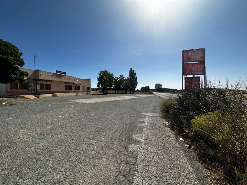 A roadside restaurant with a sign that reads 'RESTAURANTE EL MORAL' under a clear blue sky.