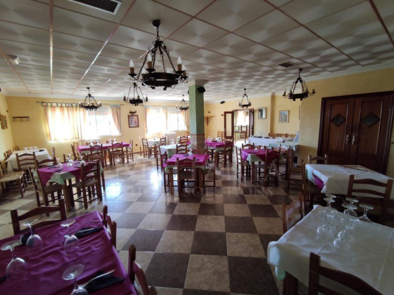 Dining room with checkered floor, chandeliers, and tables set for a meal.