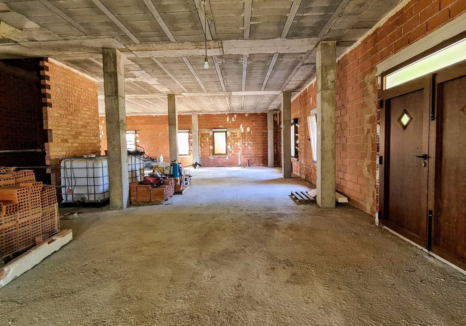 Onvoltooide binnenruimte met bakstenen muren en betonnen pilaren.