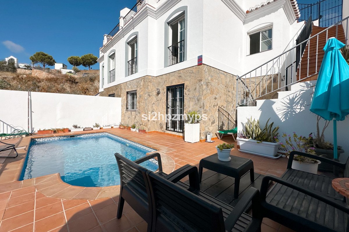 White villa with a private swimming pool, terraced patio, outdoor seating, and a blue umbrella. Sunny day.
