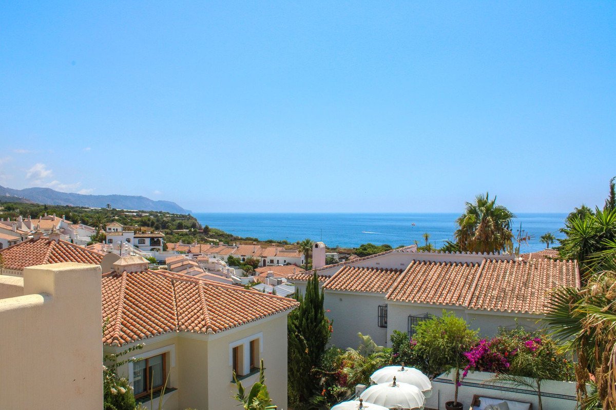 A beautiful panoramic view of Mediterranean rooftops and the sparkling sea under a clear blue sky.