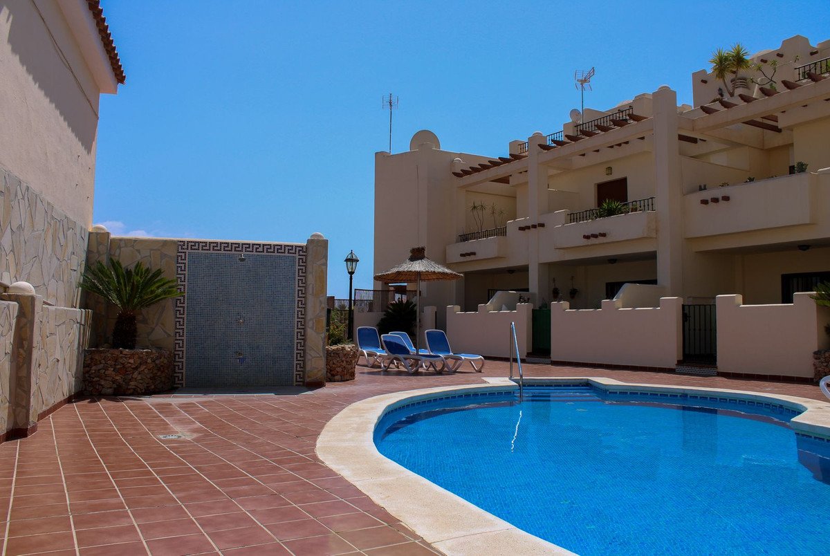 Outdoor swimming pool area with sunbeds, a parasol, and a decorative outdoor shower feature.