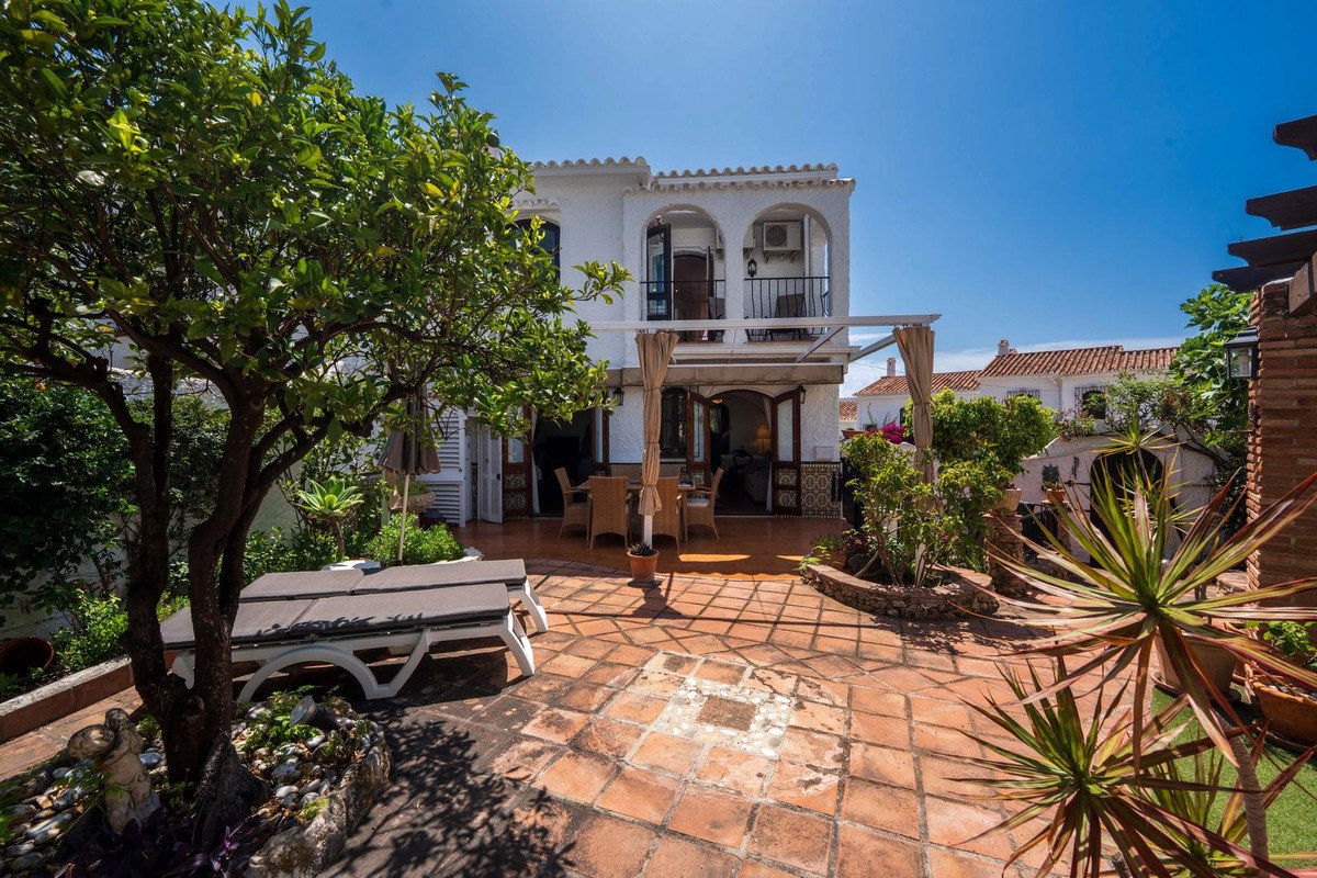 Terraced garden with patio, sun loungers, outdoor dining area, and a white villa with balconies.