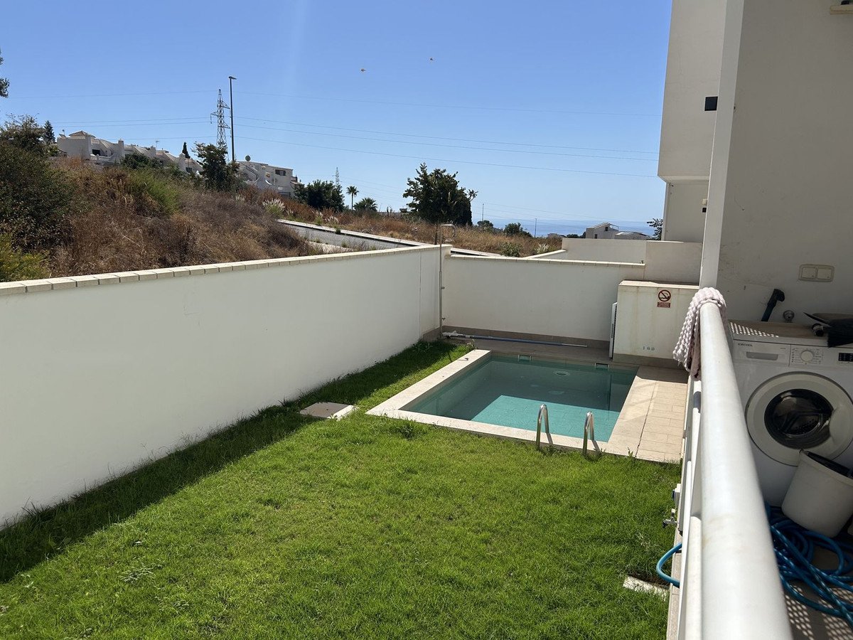 Small private pool and green garden with distant sea view, adjacent to a modern villa exterior.