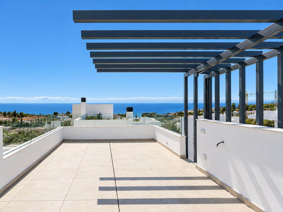 Spacious rooftop terrace with modern pergola and glass railings, offering panoramic sea and coastal views on a sunny day.