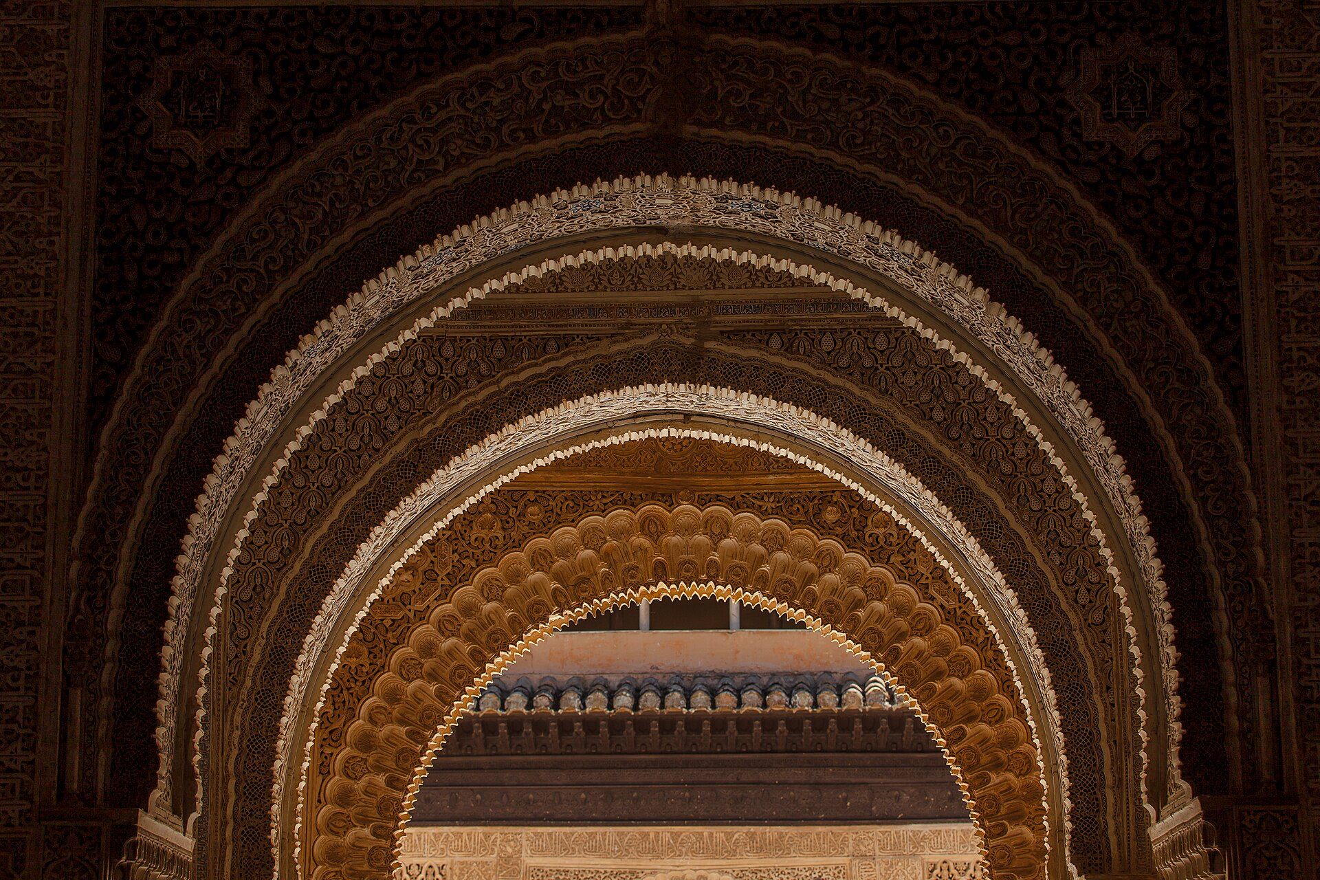 Intricate archway with detailed carvings and a view of a blue-tiled roof.