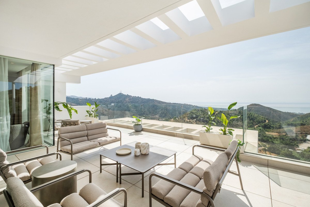 Modern terrace with seating and a coffee table, offering stunning sea and mountain views.