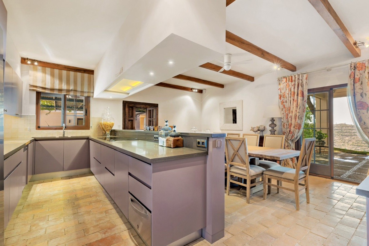 Stijlvolle keuken en eetkamer met houten balken en terracotta vloer.