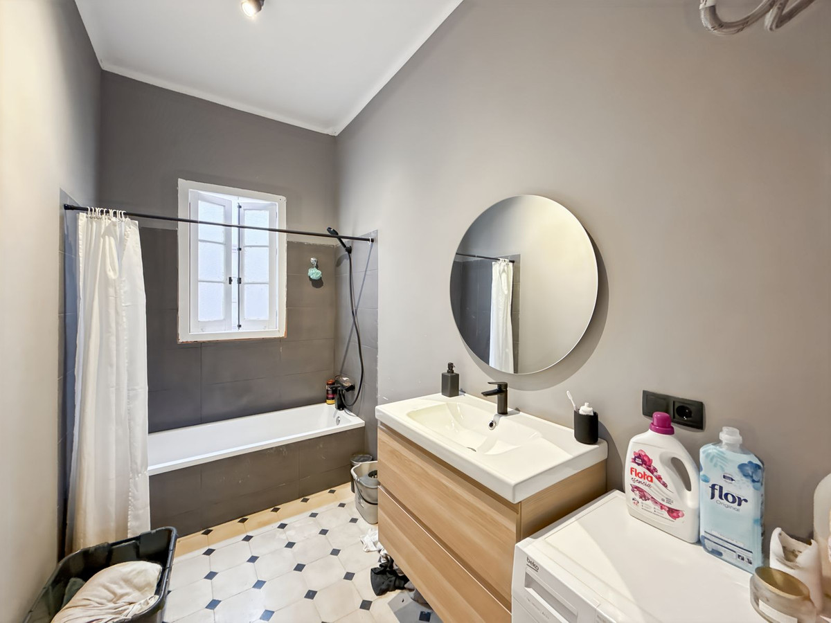 Badkamer met grijze muren, bad en moderne wastafel.