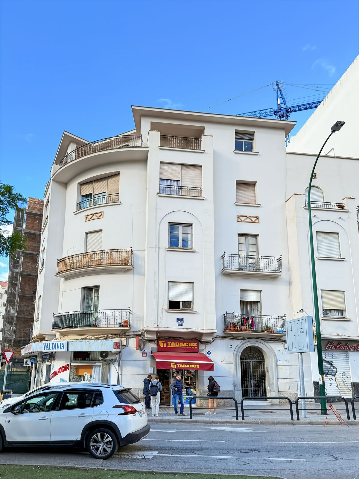 Wit gebouw met winkels op straatniveau en balkons in Spanje.